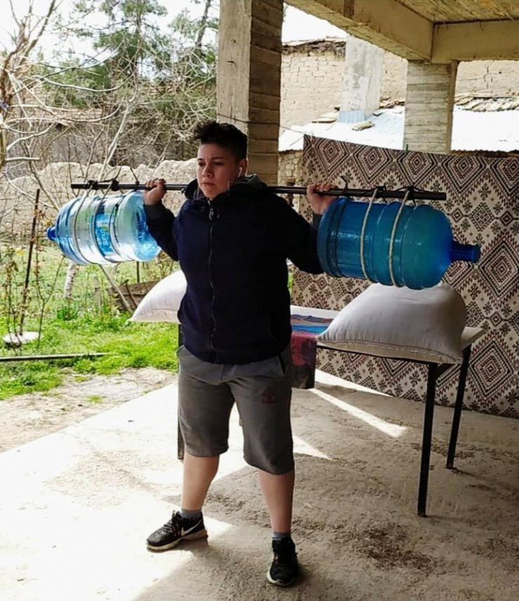 Genç kadın halterci, damacanadan yaptığı halter barlarıyla çalışıyor