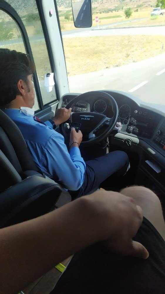 Şehirlerarası otobüs şoförünün bir elinde telefon, bir elinde çekirdek