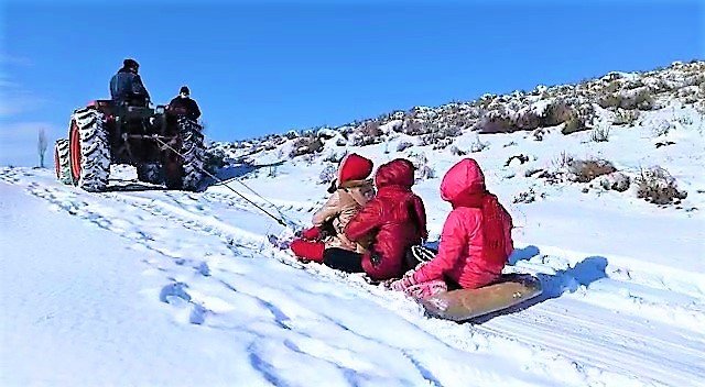 Kar yağışının tadı böyle çıkar! Traktörün arkasına kızak bağlayıp çocukları eğlendirdiler