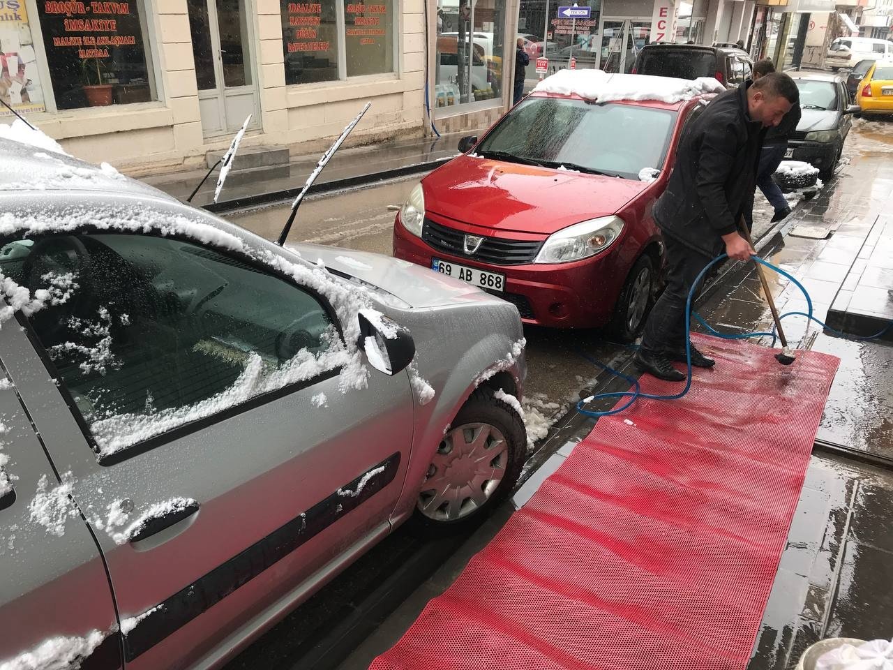 Bayburtlu esnaf kar yağışı altında paspas yıkayarak araç temizliği yaptı