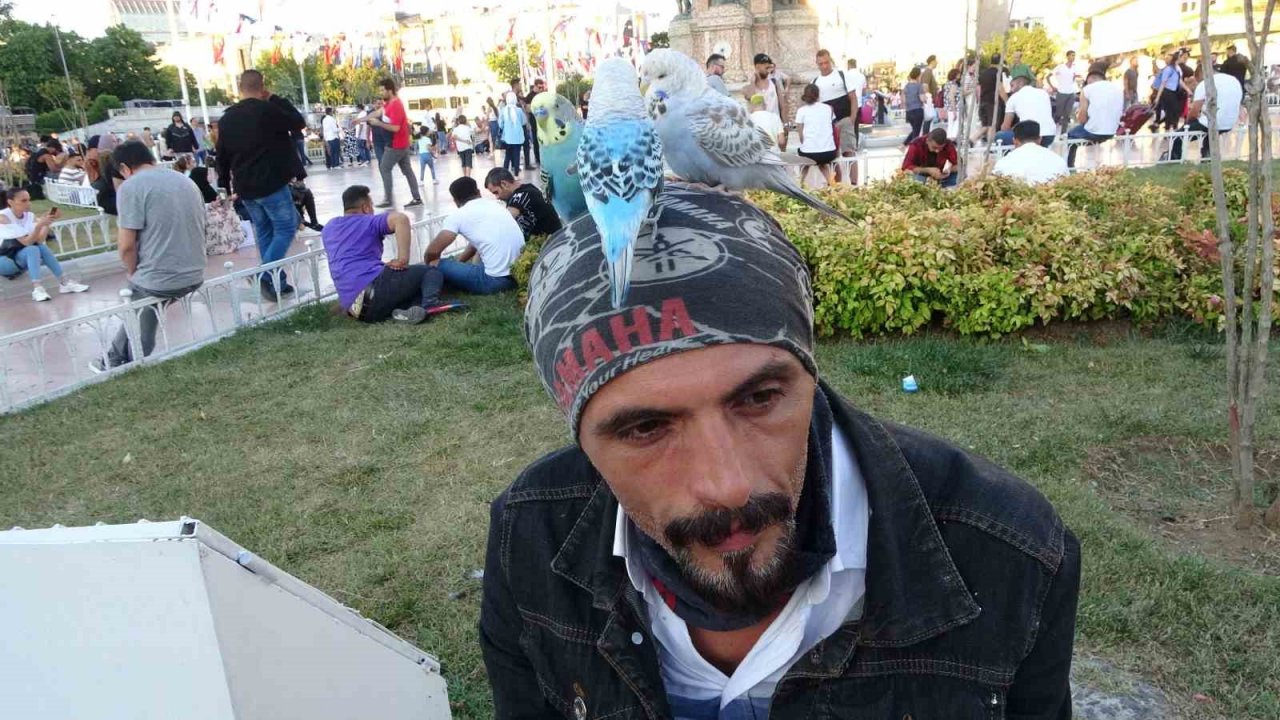 Başında gezdirdiği 3 muhabbet kuşuyla Taksim’de ilgi odağı oldu